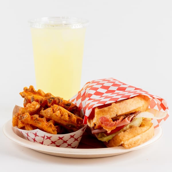 Waffles Café's waffle sandwich, waffle fries, and lemonade on a white plate.