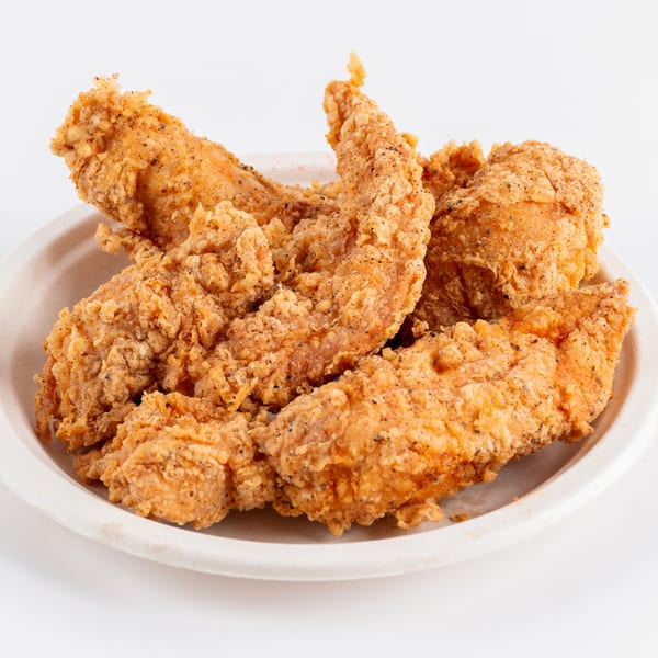 Crispy, golden-brown fried chicken tenders, seasoned with pepper, served on a light-colored plate.