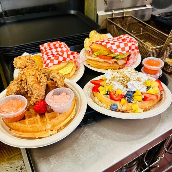 Three Waffles Café breakfast plates: chicken and waffle, waffle sandwich, and fruit waffle.