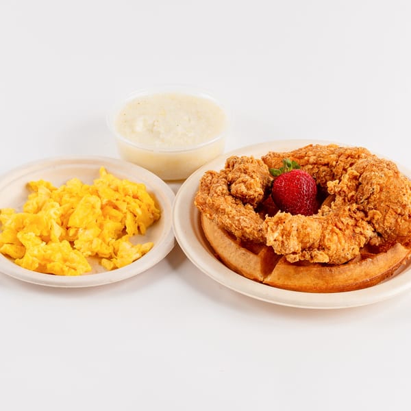 Waffles Café breakfast with chicken and waffles, scrambled eggs, and grits on a white background.
